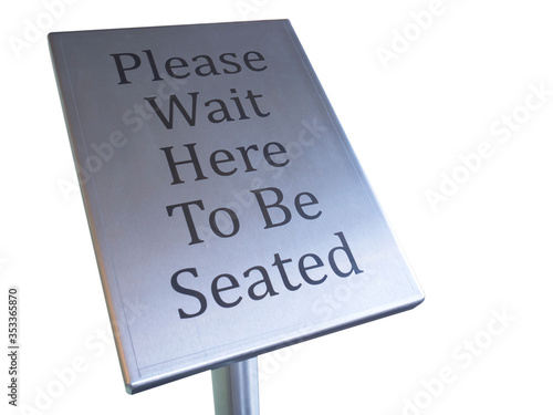 please wait here to be seated sign on white background photo