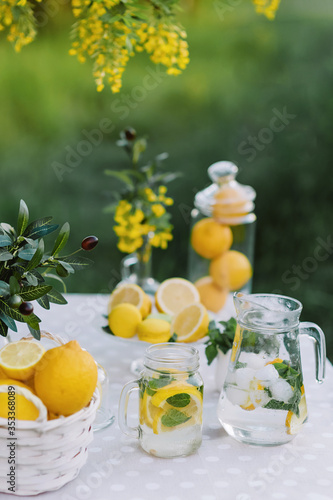 Lemonade and olive palm on table. Mason jar glass of lemonade with lemons. Copy space. Fruits and macaroons on the table. The concept of spring and summer season. Healthy Food and Drink