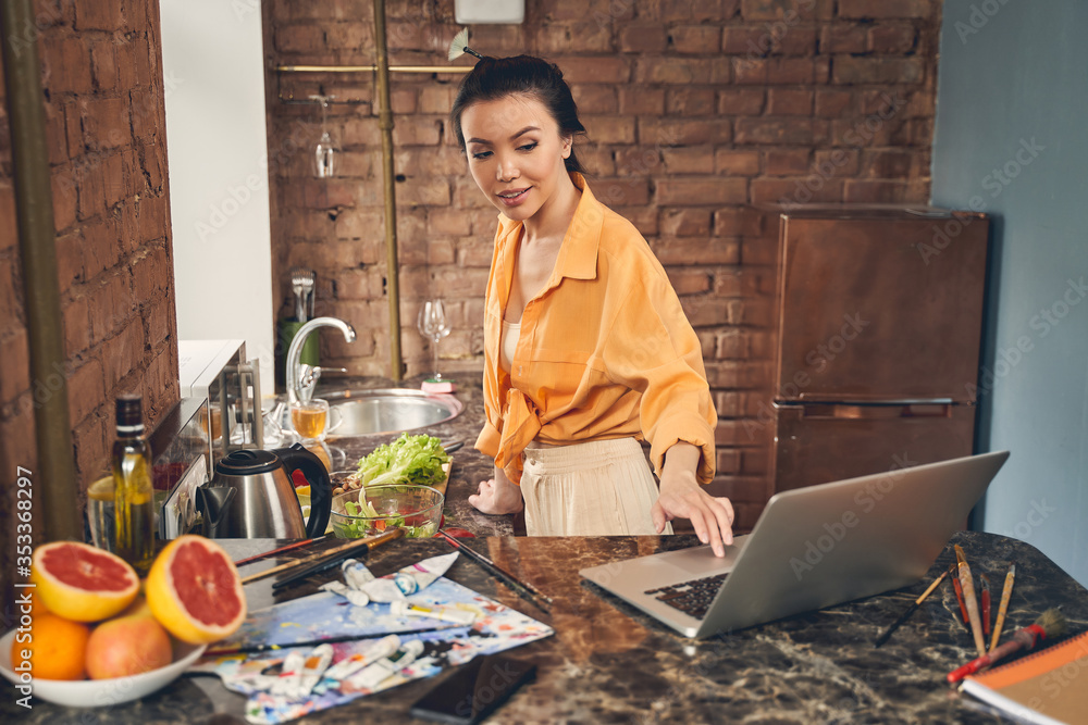 Fototapeta premium Attractive young woman using notebook in kitchen