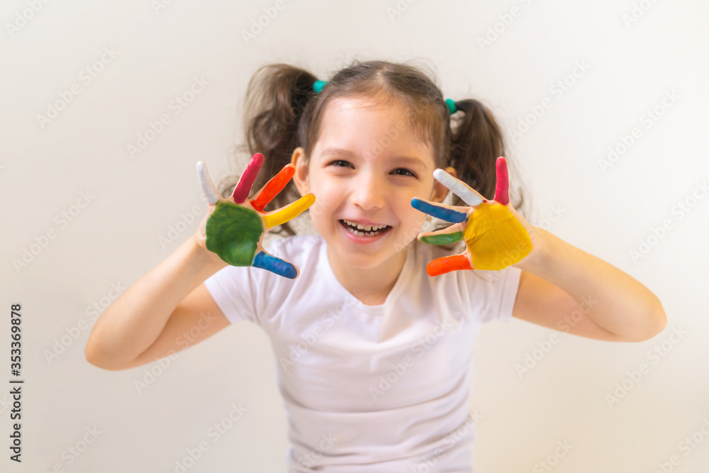 Happy little girl with painted palms on a light background Happy little girl with painted palms on a light background
