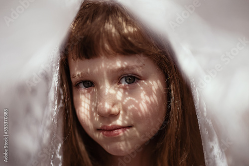 
a girl stands with a lace pattern on her face, a shadow from the sun