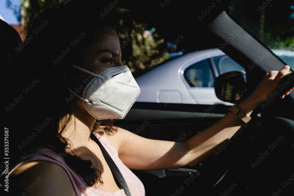 side portrait of young woman driving wearing face mask in the city side portrait of young woman driving wearing face mask in the city