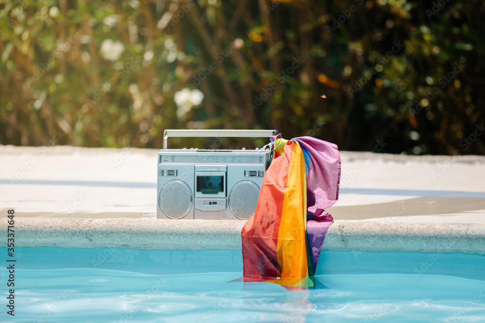 Naklejka premium Metal radio cassette with an lgtb flag attached to the handle on a pool