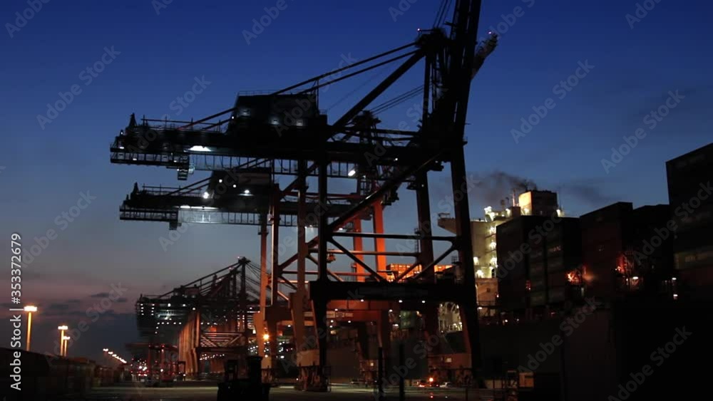 Container ship loading and unloading at sunset (blue hour) at the port of Hamburg / Germany Container ship loading and unloading at sunset (blue hour) at the port of Hamburg / Germany
