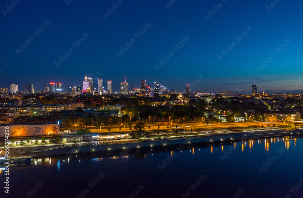 night aerial panorama of Warsaw center across Wisla river with reflection