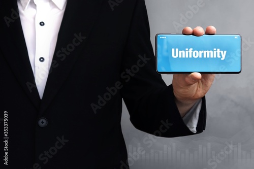 Uniformity. Businessman holding a phone in his hand. Man present screen with word. Blue Background. Business, Finance, Statistics, Analysis, Economy