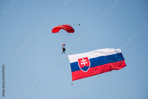Fotografie Slovak army parachutist flying from the sky with Slovak flag