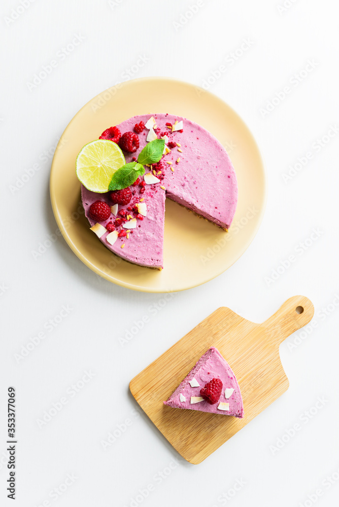 A slice of cold raw cashew cake with raspberries, mint and lime on a light table. Vegan dessert, sugar free, gluten free, lactose free. Vertical orientation, top view. A slice of cold raw cashew cake with raspberries, mint and lime on a light table. Vegan dessert, sugar free, gluten free, lactose free. Vertical orientation, top view.