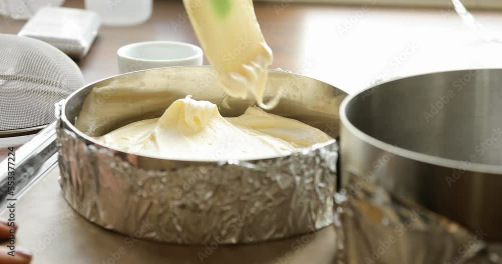 Woman is putting liquid dough in baking pan and smoothing it using spatula, closeup view. Creamy white dough for cake. Steps of baking and confectionery. Preparing sweet food dessert in kitchen. Woman is putting liquid dough in baking pan and smoothing it using spatula, closeup view. Creamy white dough for cake. Steps of baking and confectionery. Preparing sweet food dessert in kitchen.