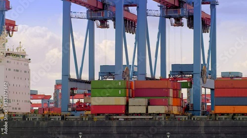 Two gantry cranes are loading container on a ship at daytime in the port of Hamburg / Germany
