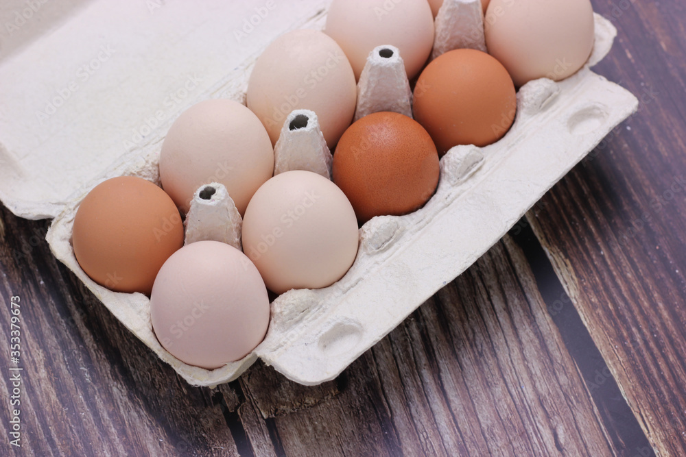 Chicken eggs in a carton on a wooden surface. Chicken eggs in a carton on a wooden surface.