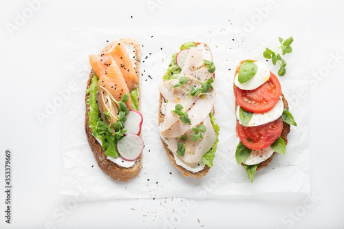 sandwiches with ham, radish, romano salad, baby basil, mascarpone cheese, caprese salad on a white background. top view.