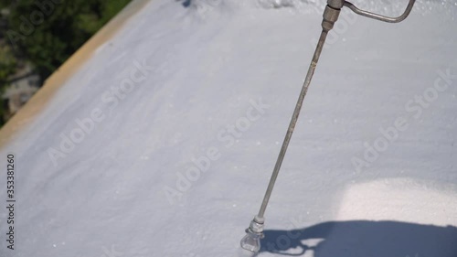 Male hand holds spray gun, uses chemical solution, paints the roof, insulates the roof