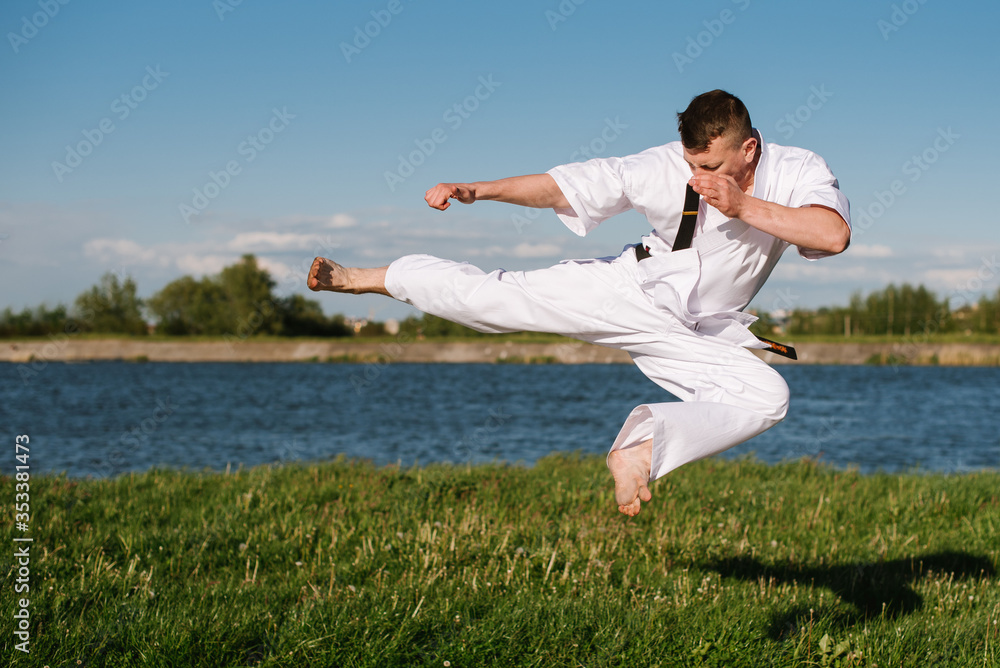 A man karate fighter in white kimono training outdoor in the park A man karate fighter in white kimono training outdoor in the park