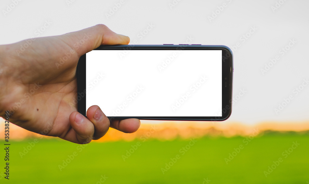 modern telephone in hand with white screen on sunset background