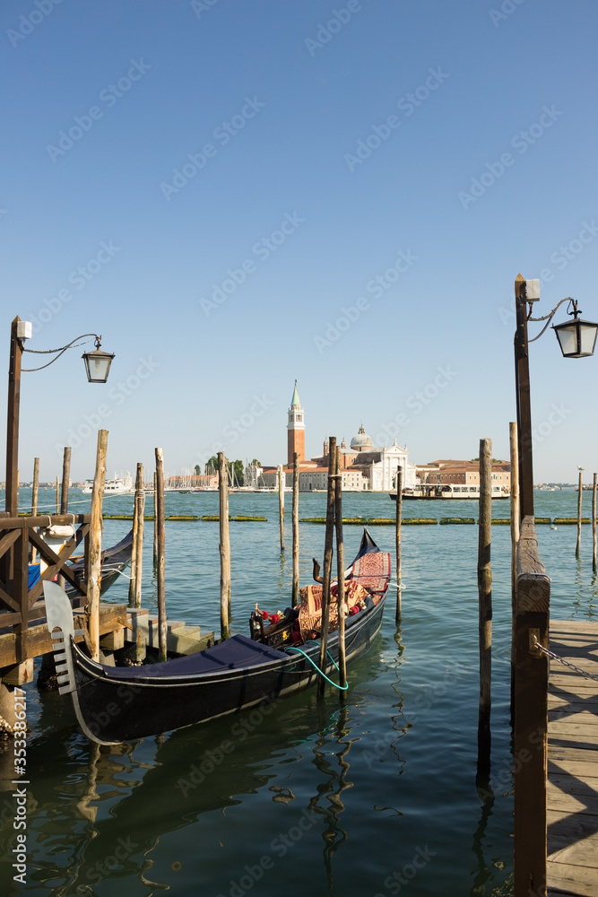 Gondolas moored on the pier of Saint Mark square (Piazza San Marco), in the background is San Giorgio di Maggiore church, Venice, Italy