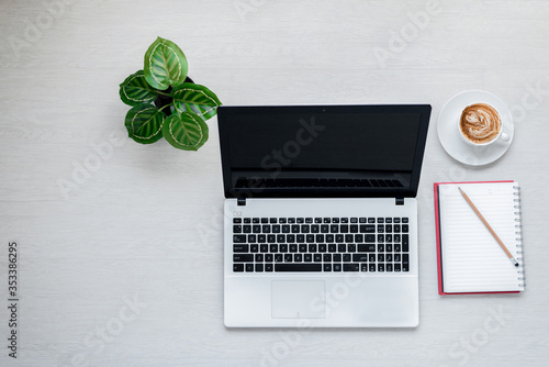 Top view of Laptop or Notebook Computers , pencil , and cup of coffee on white wooden table.