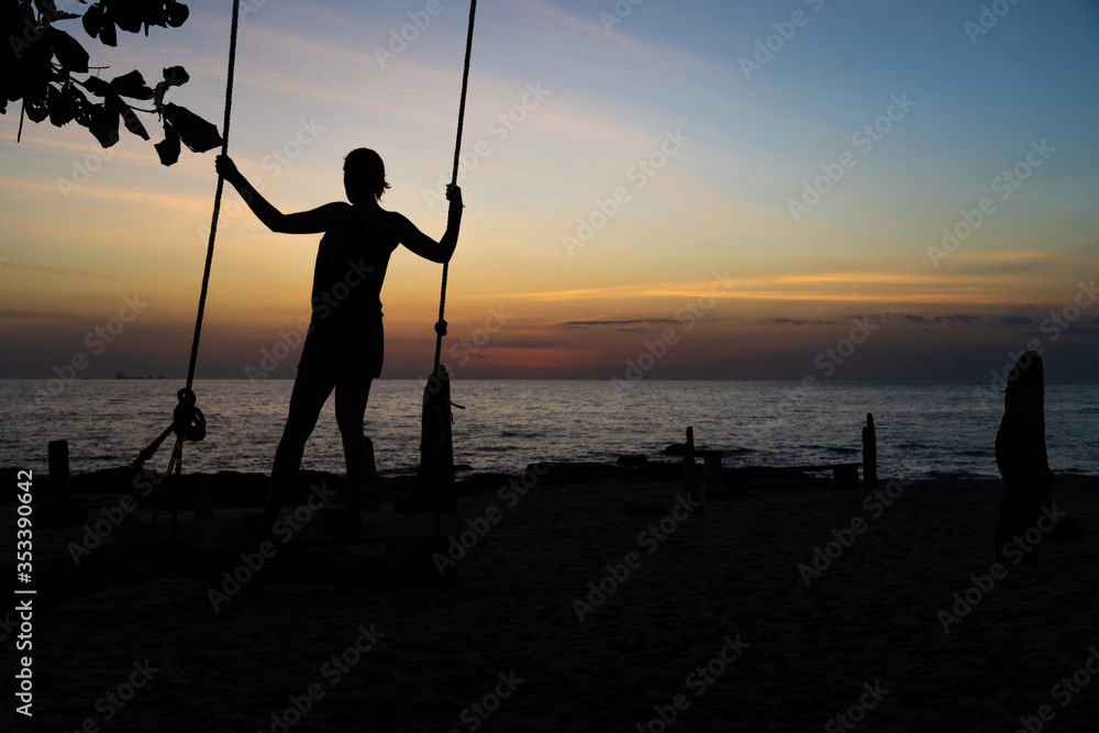 Girl on the beach on top of a swing.