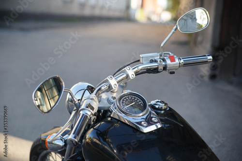Motorcycle steering wheel and dashboard on the street.