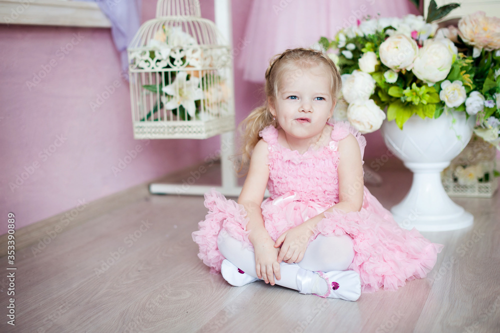 A little ballerina in a dress sits in a dance class on the floor. Legs crossed, mischievous face. Concept does not want to deal A little ballerina in a dress sits in a dance class on the floor. Legs crossed, mischievous face. Concept does not want to deal