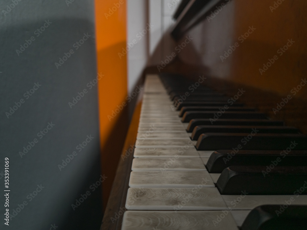 Old unused piano standing next to gray and orange wall Old unused piano standing next to gray and orange wall
