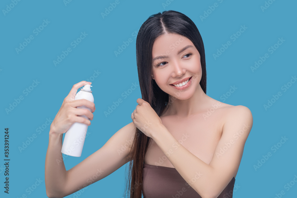 Young asian woman spraying keratin on her hair Young asian woman spraying keratin on her hair