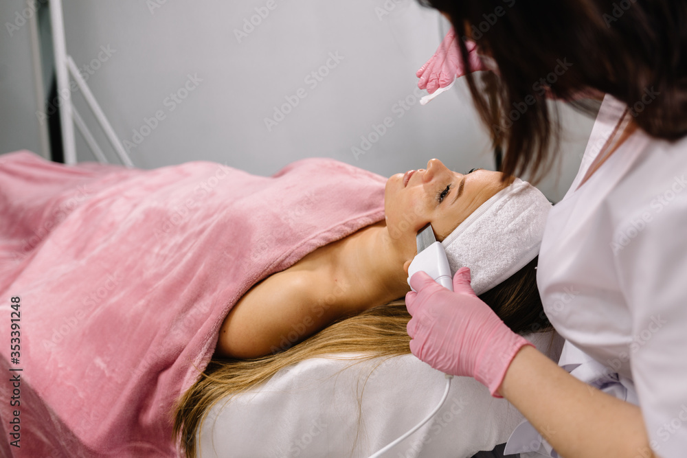 Ultrasonic scraber. Procedure of ultrasonic cleaning of face. Model, profile. Cosmetological clinic. Patient. Healthcare, clinic, cosmetology Ultrasonic scraber. Procedure of ultrasonic cleaning of face. Model, profile. Cosmetological clinic. Patient. Healthcare, clinic, cosmetology
