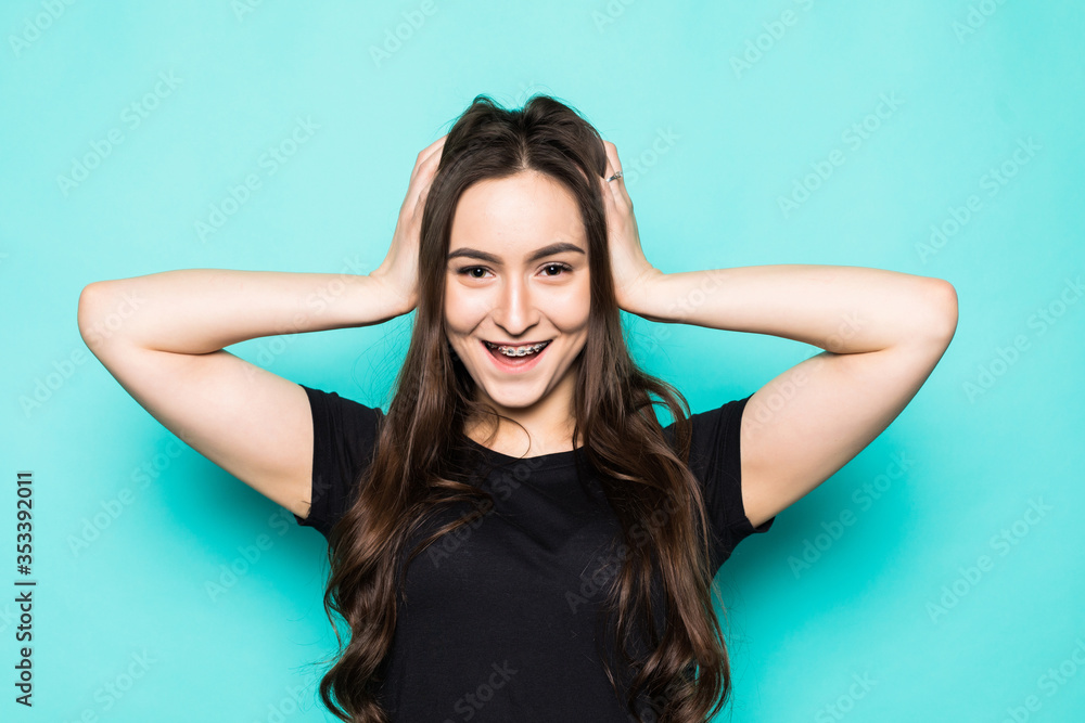 Young beautiful woman with hands over head standing over blue background