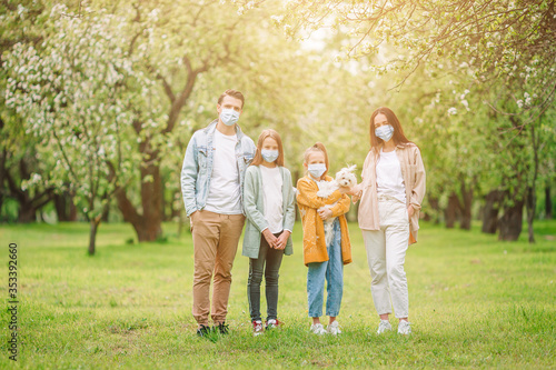 Adorable family in blooming cherry garden in masks