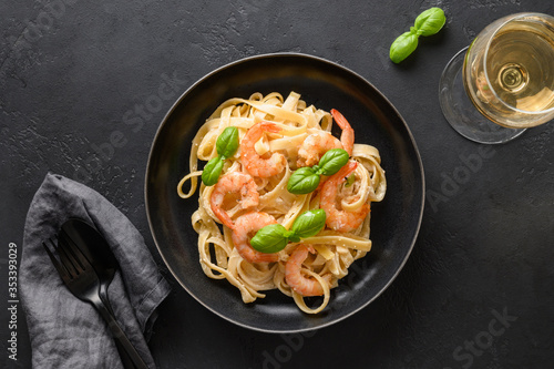 Italian fettuccine with shrimps, seafood served wine glass on black. View from above.