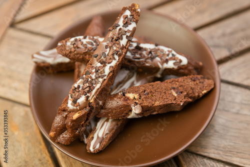 chocolate homemade biscotti cookies with white and dark chocolate on a brown plate on a wooden table