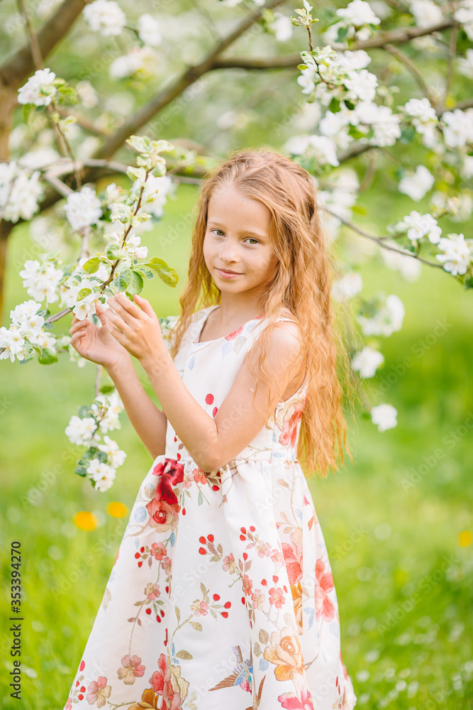 Adorable little girl in blooming apple garden on beautiful spring day