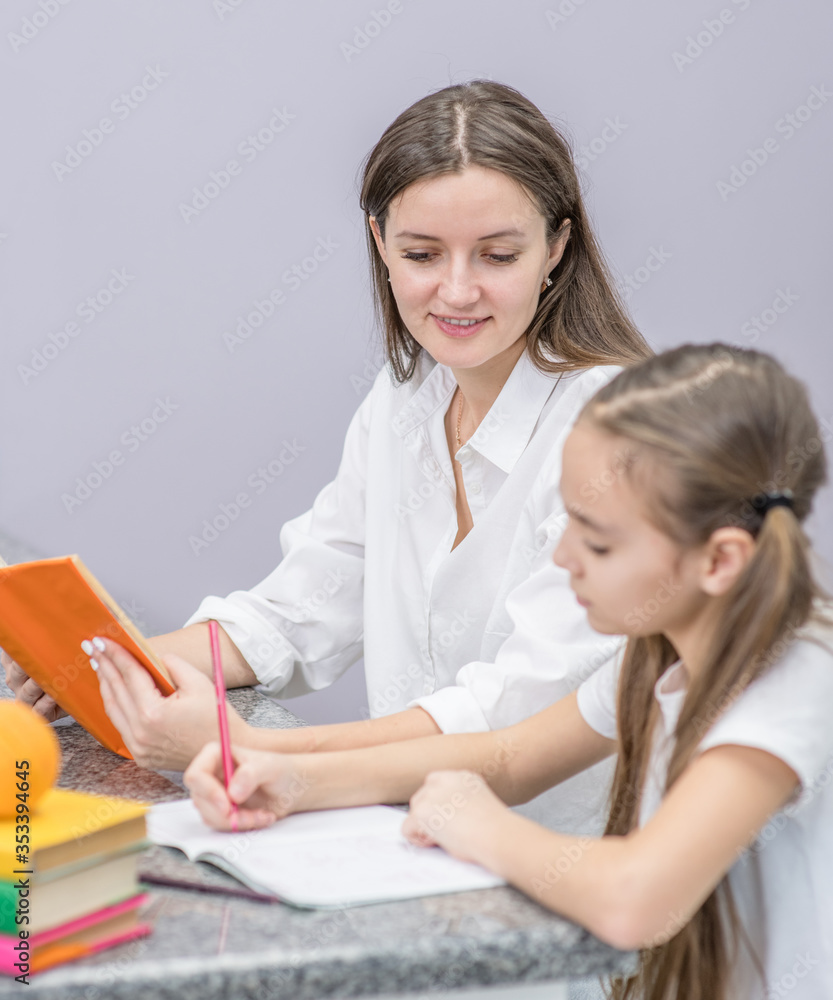 Happy family at home. Smiling mom helps her daughter do homework Happy family at home. Smiling mom helps her daughter do homework