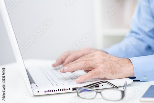 Close up senior man typing on laptop in a office
