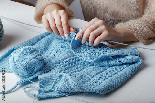 woman knits handmade woolen blue sweater on the table