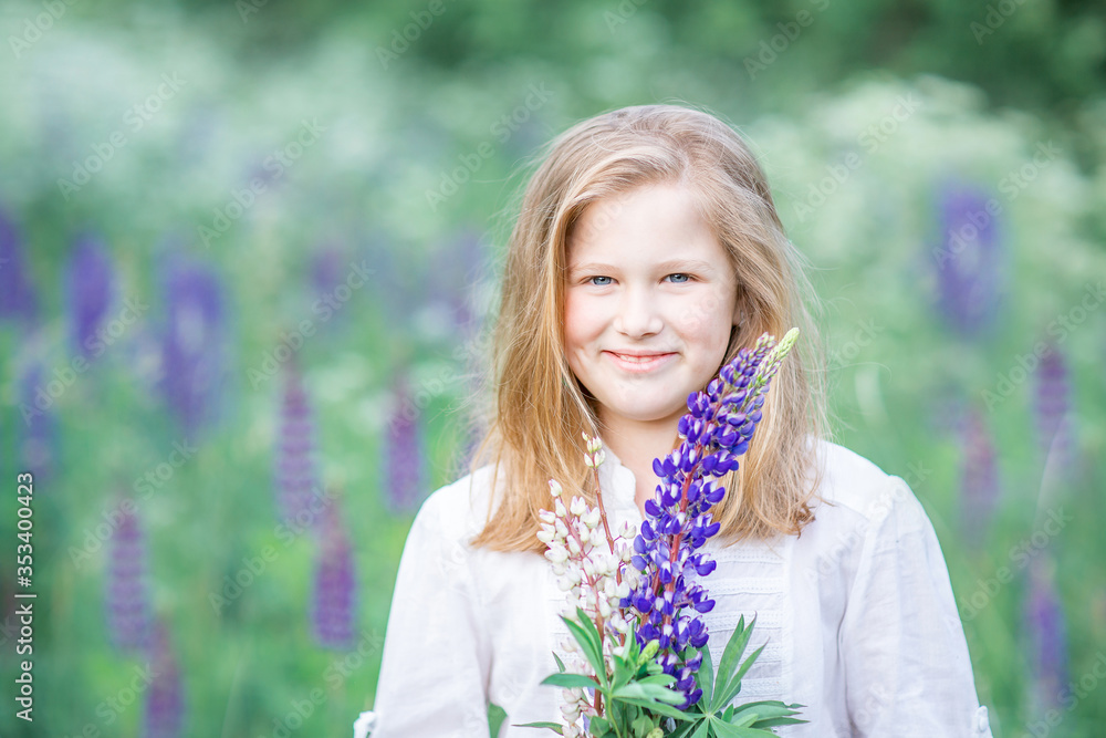 Portrait of a fair-haired 10-year-old girl in a field with lilac flowers. Smiling, holding lilac flowers in her hands Portrait of a fair-haired 10-year-old girl in a field with lilac flowers. Smiling, holding lilac flowers in her hands
