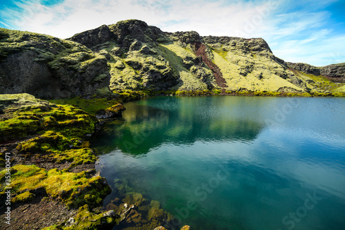 Fototapeta Naklejka Na Ścianę i Meble -  Volcanic lake inside of a crater in Iceland. Volcanic crater lake in southern Iceland. Highland of Iceland. Beautiful crater lake with a turquoise water color covered with green moss