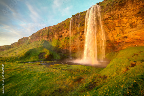 Waterfall Selandjafoss Iceland at sunset or sunrise. Beautiful waterfall in Iceland. Golden hour. Cave and waterfall. Travel in Iceland. Beautiful sky against the big waterfall. inside the water. 