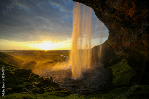Obraz na płótnie Waterfall Selandjafoss Iceland at sunset or sunrise. Beautiful waterfall in Iceland. Golden hour. Cave and waterfall. Travel in Iceland. Beautiful sky against the big waterfall. inside the water. w salonie