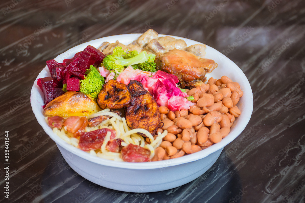 Deliver food, marmita ou marmitex with rice, beans, beets, broccoli, mayonnaise with vegetables, fried chicken, beef stroganoff, pasta and bacon on a dark marble table. Deliver food, marmita ou marmitex with rice, beans, beets, broccoli, mayonnaise with vegetables, fried chicken, beef stroganoff, pasta and bacon on a dark marble table.