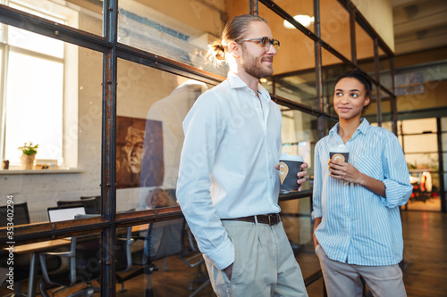 Photo of multinational joyful colleagues talking and drinking coffee