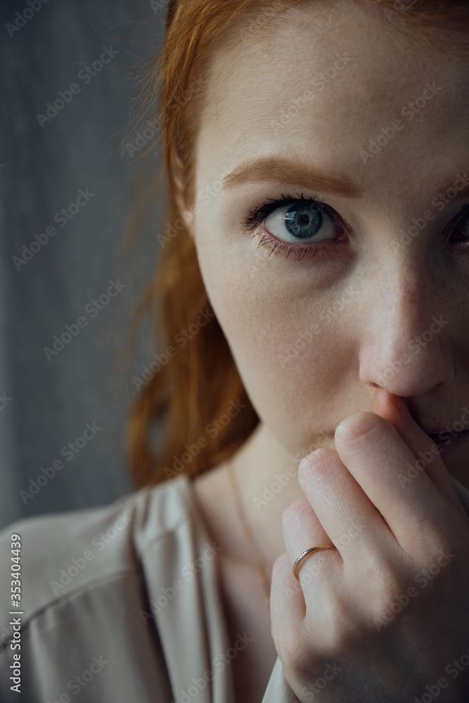 Close shot of half face of red-haired girl with blue eyes. A look into the frame, a hand at the lips. Focus on the face. Close shot of half face of red-haired girl with blue eyes. A look into the frame, a hand at the lips. Focus on the face.