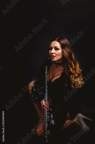 Female in an artist's costume with flute on black background. Flute in hand. Stylish girl with musical instrument (flute). Photo for magazine cover, website with space for an inscription or logo