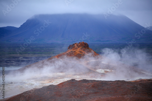 Geothermal region of Hverir in Iceland near Myvatn Lake, Iceland. Sulfur colored land and red roicks creek with steam. Volcanic rocks. Lava field. Icelandic volcanic mountain expanse of hot springs