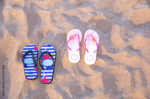 a pair of male and female flip flops in the sand on the beach