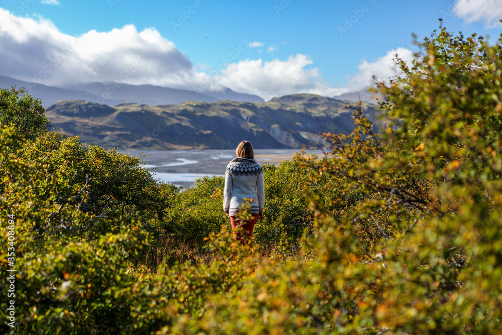 Girl on Iceland in Icelandic sweater. Adventure woman by Thorsmork Iceland. Tourist in Icelandic sweater in green trees landscape. Icelandic girl