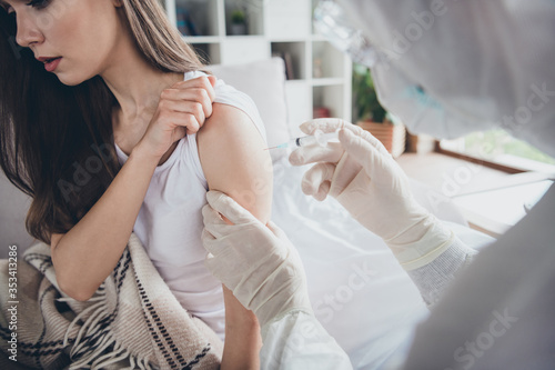 Photo of young sick ill patient lady sit sofa unwell call emergency doc virologist flu cold covid injection hand shoulder medication help wear latex gloves protective uniform indoors