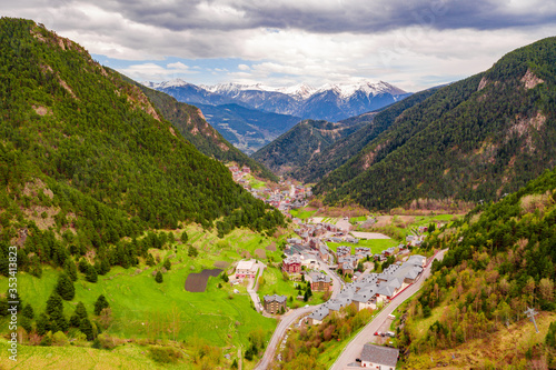 Aerial drone view of a valley and small village in middle of the mountains in Andorra with snow on top