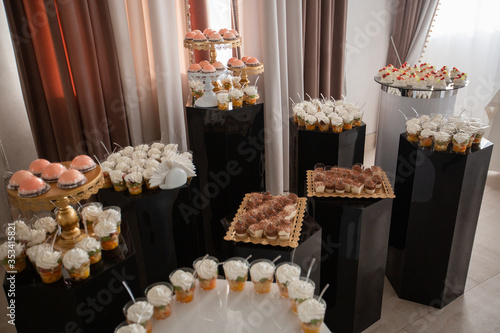 Table with sweets, buffet with cupcakes, candies. Candy bar, a table with sweets and desserts. Buffet with delicious cupcakes, cake pops, biscuits. Wedding, birthday and surprise concept.