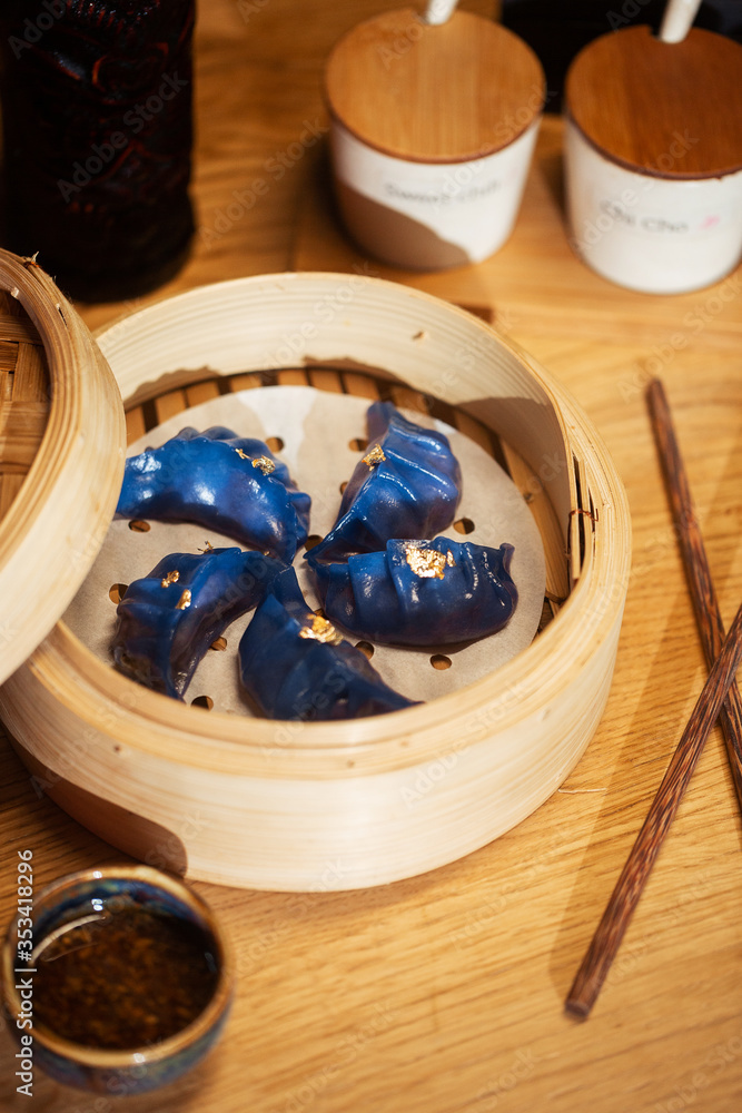 Blue Dim Sum chinese cuisine in bamboo steamer and pot. Top view fresh dumplings with hot steams on wood plate with chopsticks. High angled view of cooked dumplings .